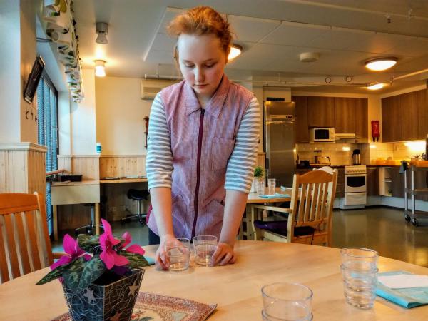 Työharjoittelija kattaa palvelukodin ruokapöytiä