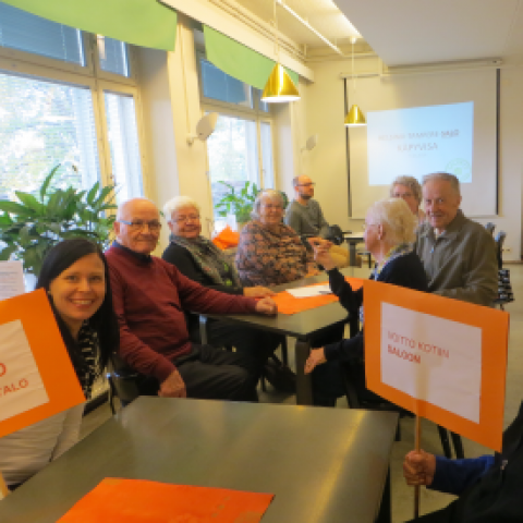 Ikäihmiset ovat pöydän ympärillä pelaamassa tietovisaa